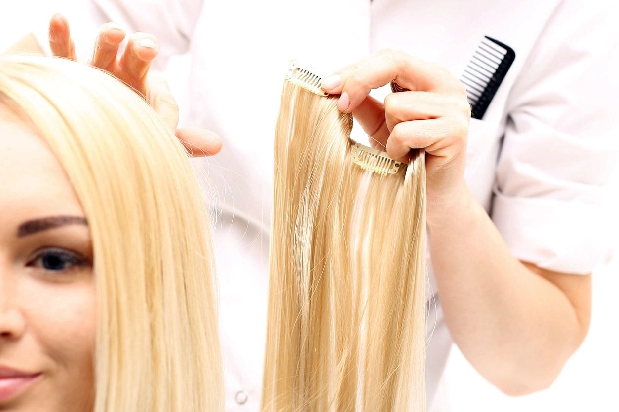 A woman is cutting her hair with scissors.