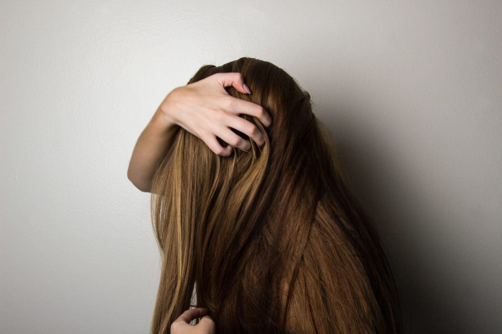 A woman with long brown hair is combing her hair.
